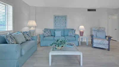 a living room with blue couches and a table at Sand Cliffs 214 in Seacrest