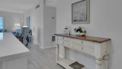 a white kitchen with a table with a vase on it at Sand Cliffs 214 in Seacrest