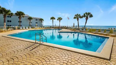 a large swimming pool with palm trees and the ocean at Sand Cliffs 214 in Seacrest