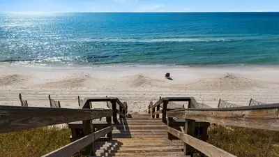 a wooden staircase leading to a beach with the ocean at Sand Cliffs 214 in Seacrest