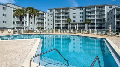 a swimming pool with chairs and a building at Sand Cliffs 415 in Seacrest