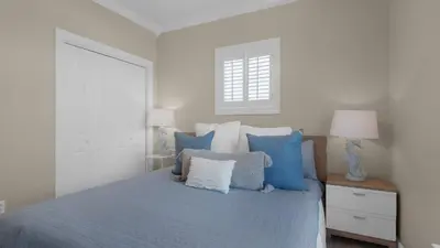 a bedroom with a bed with blue pillows and a window at A Slice of Lime in Santa Rosa Beach