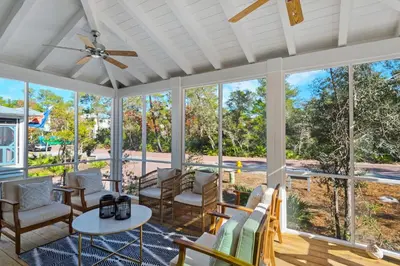 a screened porch with chairs and a ceiling fan at Après Sea in Seacrest