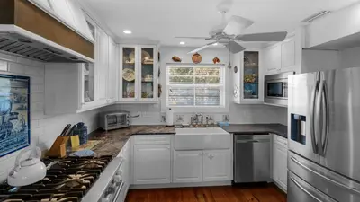 a white kitchen with white cabinets and a ceiling fan at Intensive Care in Santa Rosa Beach