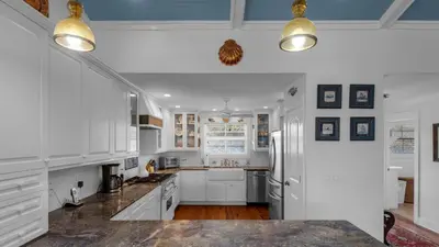 a white kitchen with white cabinets and a refrigerator at Intensive Care in Santa Rosa Beach
