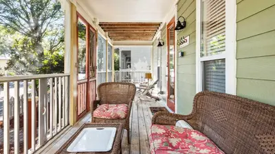 a porch with two wicker chairs and a table at Emerald Rose in Santa Rosa Beach