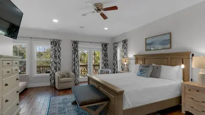 a bedroom with a bed and a chair and windows at 3 Mermaids Haven in Santa Rosa Beach
