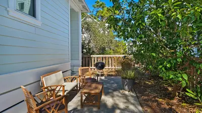 a patio with chairs and a table next to a house at 3 Mermaids Haven in Santa Rosa Beach
