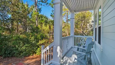 a porch with a blue bench and trees at 3 Mermaids Haven in Santa Rosa Beach