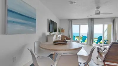 a dining room with a table and chairs and the ocean at Blue Tide 6A in Panama City Beach