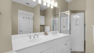 a white bathroom with two sinks and a mirror at Monterey Condos B402 in Panama City Beach