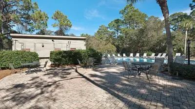 a patio with a table and chairs next to a pool at Cassine Gardens 219 - Flamingo Retreat in Santa Rosa Beach