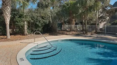 a swimming pool in a yard with palm trees at Cassine Gardens 219 - Flamingo Retreat in Santa Rosa Beach