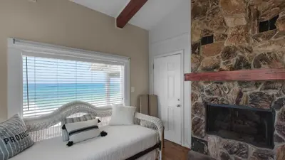 a room with a stone fireplace and a wicker chair at Paradise Cottage Too in Santa Rosa Beach