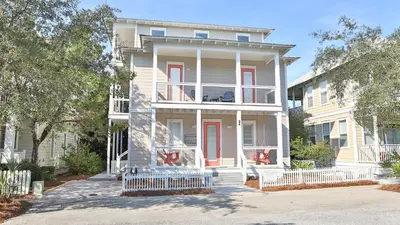 a white house with red doors and a balcony at Memory Maker in Santa Rosa Beach