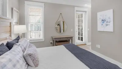 a white bedroom with a bed and a mirror at Walking on Sunshine - Benchmark Management in Panama City Beach