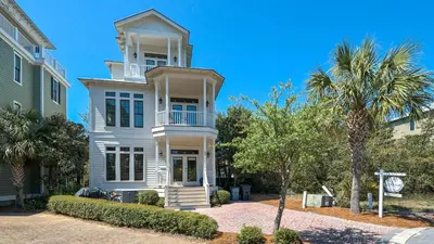 a white house with a palm tree in front of it at Ocean Breeze in Santa Rosa Beach
