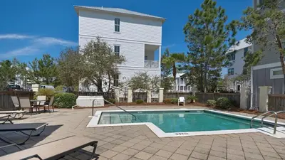 a swimming pool in front of a white building at Ocean Breeze in Santa Rosa Beach