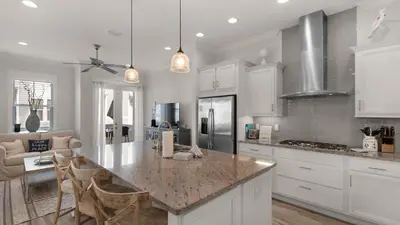 a kitchen with white cabinets and a island with chairs at Our Happy Place in Inlet Beach