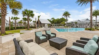 a patio with furniture and a swimming pool with palm trees at Our Happy Place in Inlet Beach