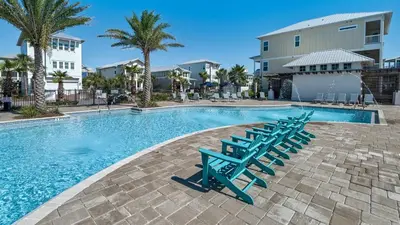 a swimming pool with blue chairs and palm trees at Our Happy Place in Inlet Beach
