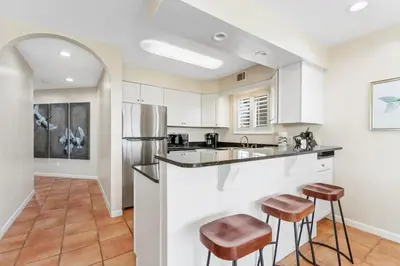 a kitchen with white cabinets and bar stools at Capistrano E101 in Seacrest