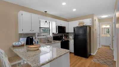 a kitchen with white cabinets and a black refrigerator at Beachwood Villas 14B - Simply Seagrove in Santa Rosa Beach