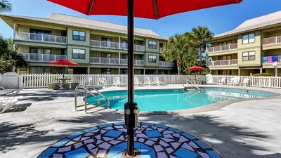 a pool with a red umbrella in front of a building at Beachwood Villas 14B - Simply Seagrove in Santa Rosa Beach