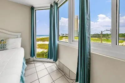 a bedroom with a bed and windows with a view of the beach at Top of the Gulf 324 in Panama City Beach