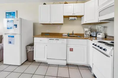 a kitchen with white cabinets and a white refrigerator at Top of the Gulf 324 in Panama City Beach