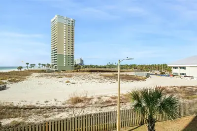 a building on the beach with a fence and a beach at Top of the Gulf 324 in Panama City Beach