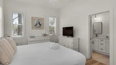 a white bedroom with a bed and a tv at Sublime in Seagrove Beach