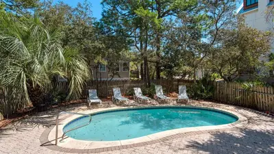 a swimming pool with lounge chairs and a fence at Sublime in Seagrove Beach