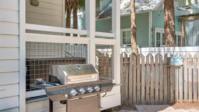 a grill on the side of a house with a fence at Sublime in Seagrove Beach