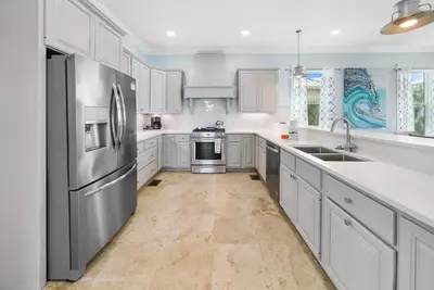 a kitchen with white cabinets and a stainless steel refrigerator at The Retreat in Santa Rosa Beach