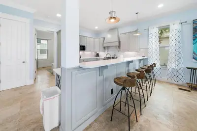 a kitchen with white cabinets and bar stools at The Retreat in Santa Rosa Beach