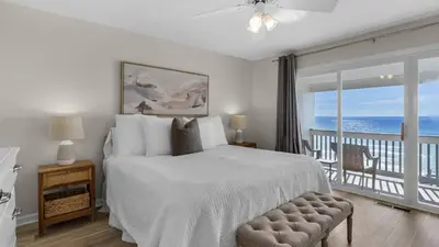a bedroom with a bed and a balcony with the ocean at Blue Nine 5 in Panama City Beach