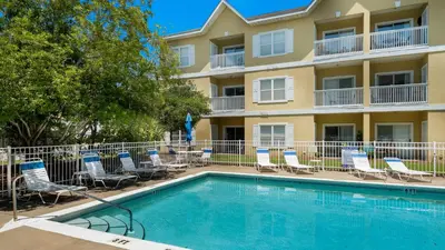 a swimming pool in front of a hotel with chairs and a building at Heron's Watch 5101 in Santa Rosa Beach