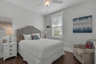 a white bedroom with a bed and a chair at 9 Prairie Pass in Santa Rosa Beach