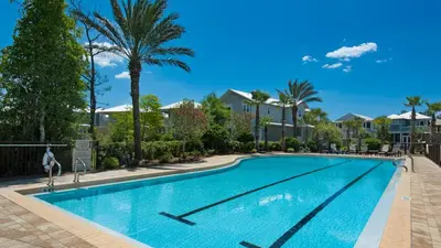 a swimming pool with palm trees and houses at 9 Prairie Pass in Santa Rosa Beach