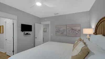 a white bedroom with a bed and a flat screen tv at Villas at Seagrove A202 - Sandcastles at Seagrove in Santa Rosa Beach