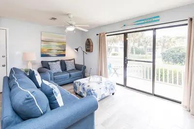 a living room with blue furniture and a sliding glass door at Beachwood Villas #9E - Sandy Cheeks in Santa Rosa Beach