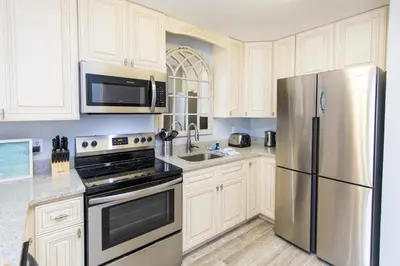 a kitchen with white cabinets and a stainless steel refrigerator at Beachwood Villas #9E - Sandy Cheeks in Santa Rosa Beach