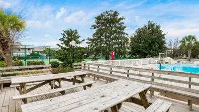 a couple of wooden benches next to a pool at Beachwood Villas #9E - Sandy Cheeks in Santa Rosa Beach
