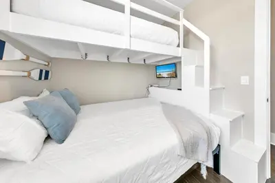 a white bedroom with a bed and two bunk beds at Bluegrass by the Sea in Santa Rosa Beach