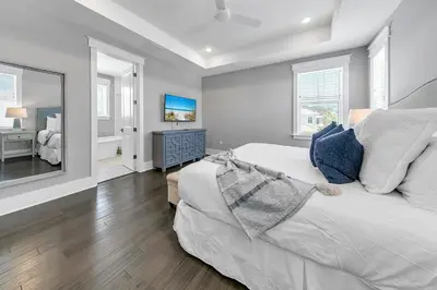 a bedroom with a white bed and a mirror at Bluegrass by the Sea in Santa Rosa Beach