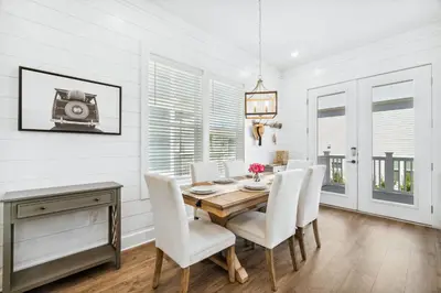 a dining room with a wooden table and white chairs at 30A Beach House - Mira Bella in Rosemary Beach