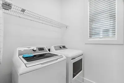 a white kitchen with a stove and a window at 30A Beach House - Mira Bella in Rosemary Beach