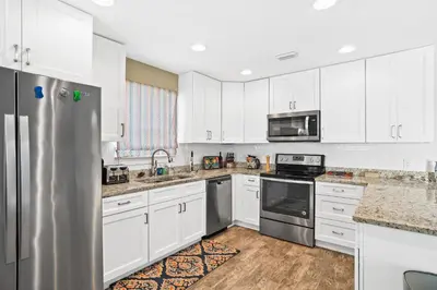 a kitchen with white cabinets and a stainless steel refrigerator at Pet Friendly Beach House - Paradise on Palm by Panhandle Getaways in Panama City Beach