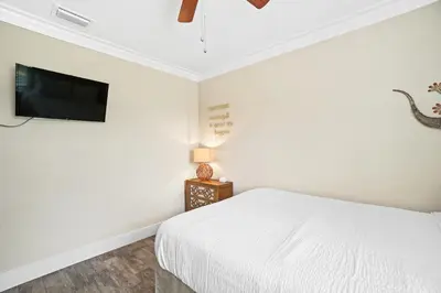 a white bedroom with a bed and a flat screen tv at Pet Friendly Beach House - Paradise on Palm by Panhandle Getaways in Panama City Beach